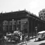 grayscale photo of people walking on street near building